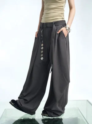 Dark gray pleated balloon wide-leg pants shown from a three-quarter side view with draped front panels and detachable geometric chain belt