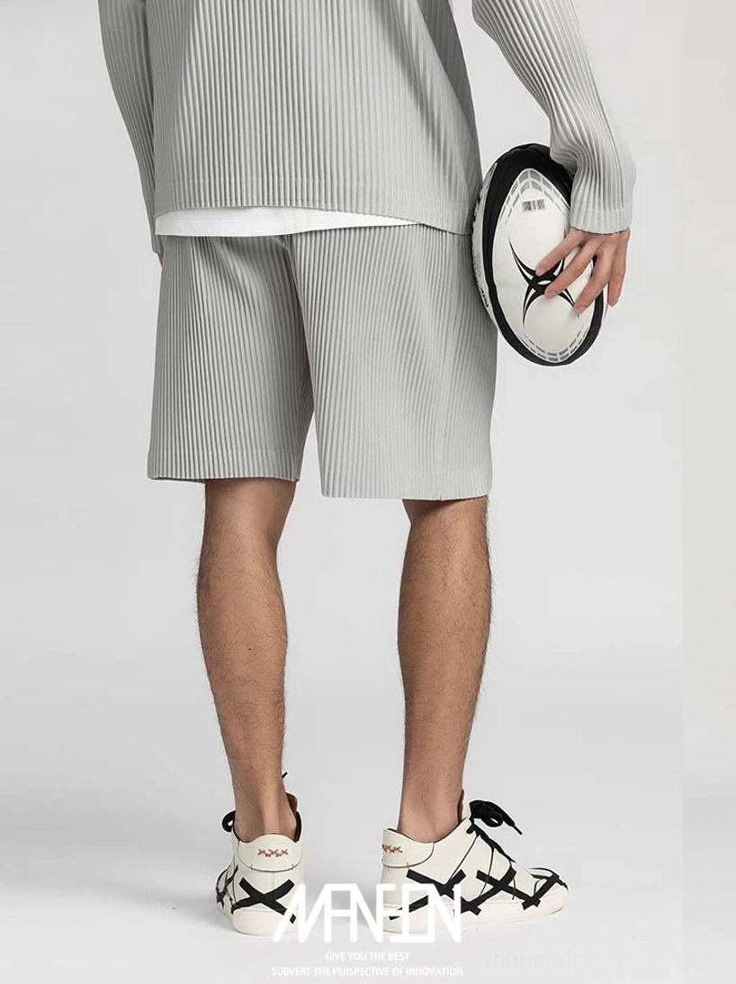 Light gray pleated tech shorts styled with a matching long sleeve top and two tone casual sneakers