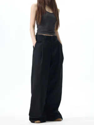 Female model wearing black high waisted pleated wide leg dress pants with an ultra loose Korean streetwear silhouette