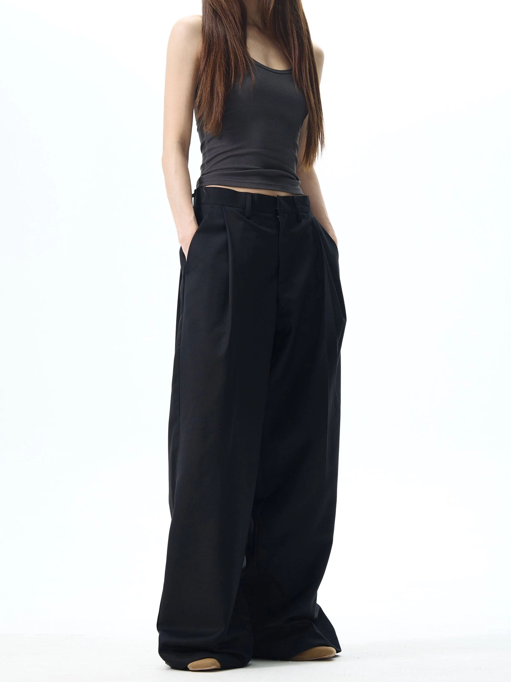 Female model wearing black high waisted pleated wide leg dress pants with an ultra loose Korean streetwear silhouette