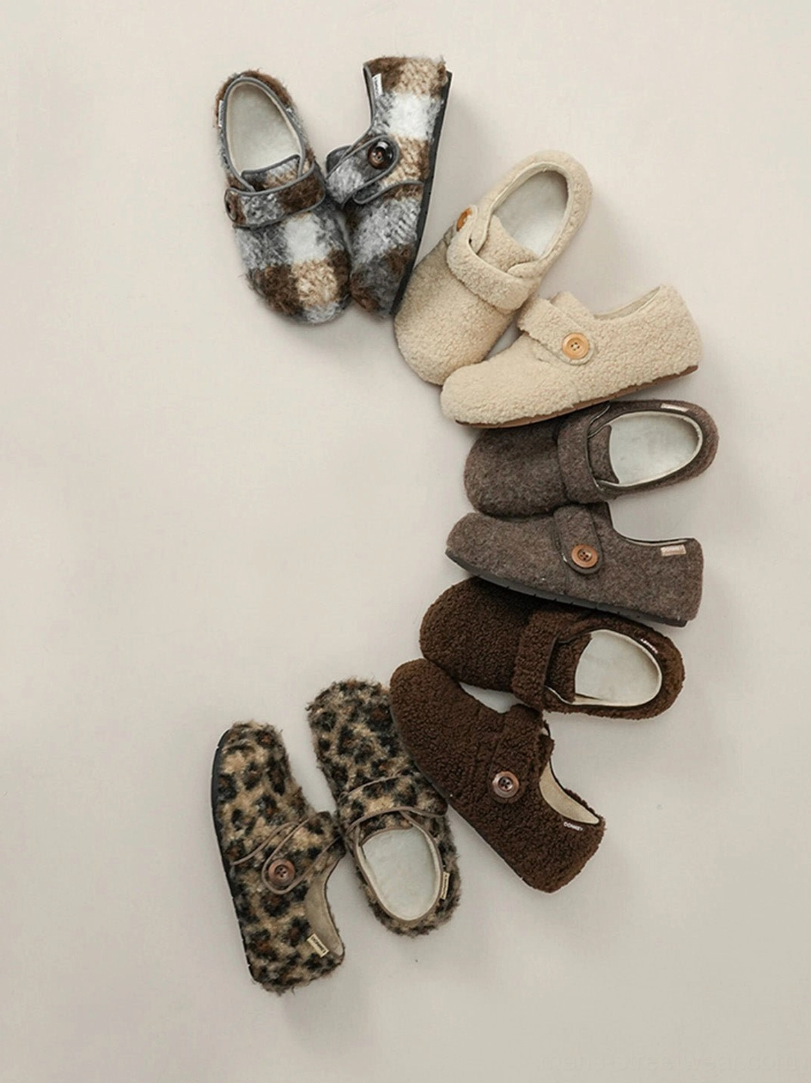 Overhead flat lay of plush faux fur Velcro slip-on shoes with round toes and button straps