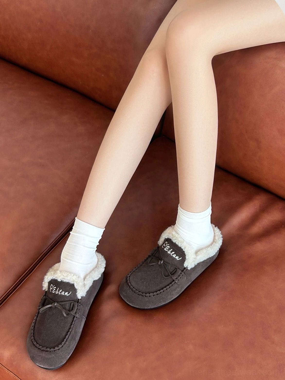Plush-lined suede-look moccasin slippers with cozy open-back silhouette and decorative lace detail