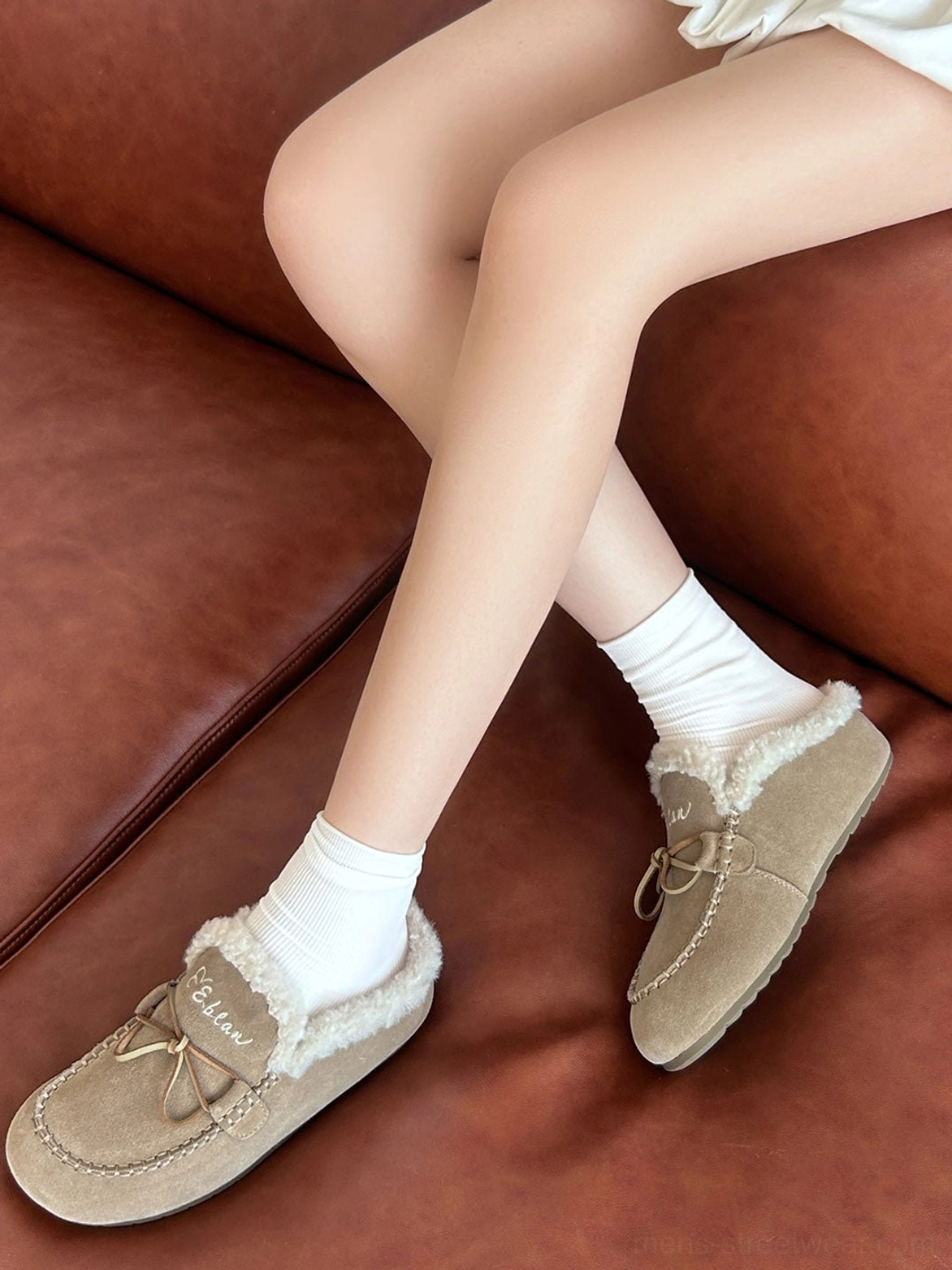 Sand color plush-lined moccasin slippers worn with white socks for a relaxed cozy streetwear outfit