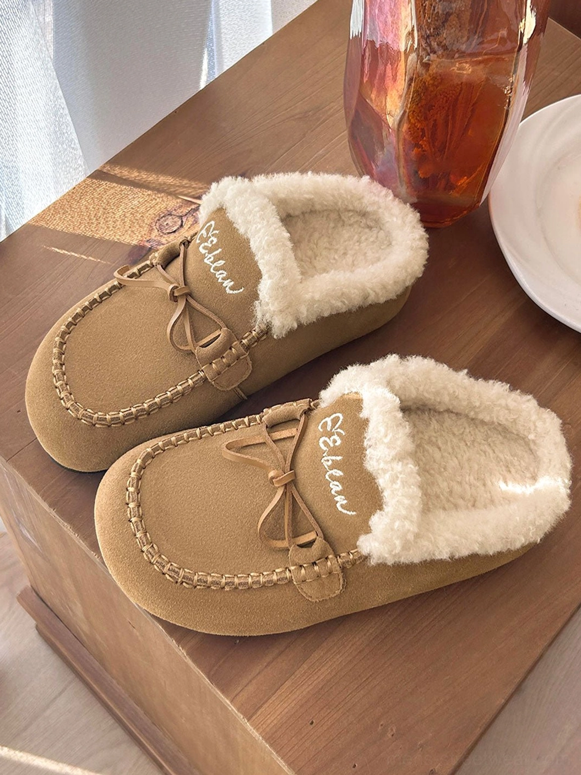 Tan suede-look moccasin slippers with plush fleece lining shown in an overhead lifestyle flat lay