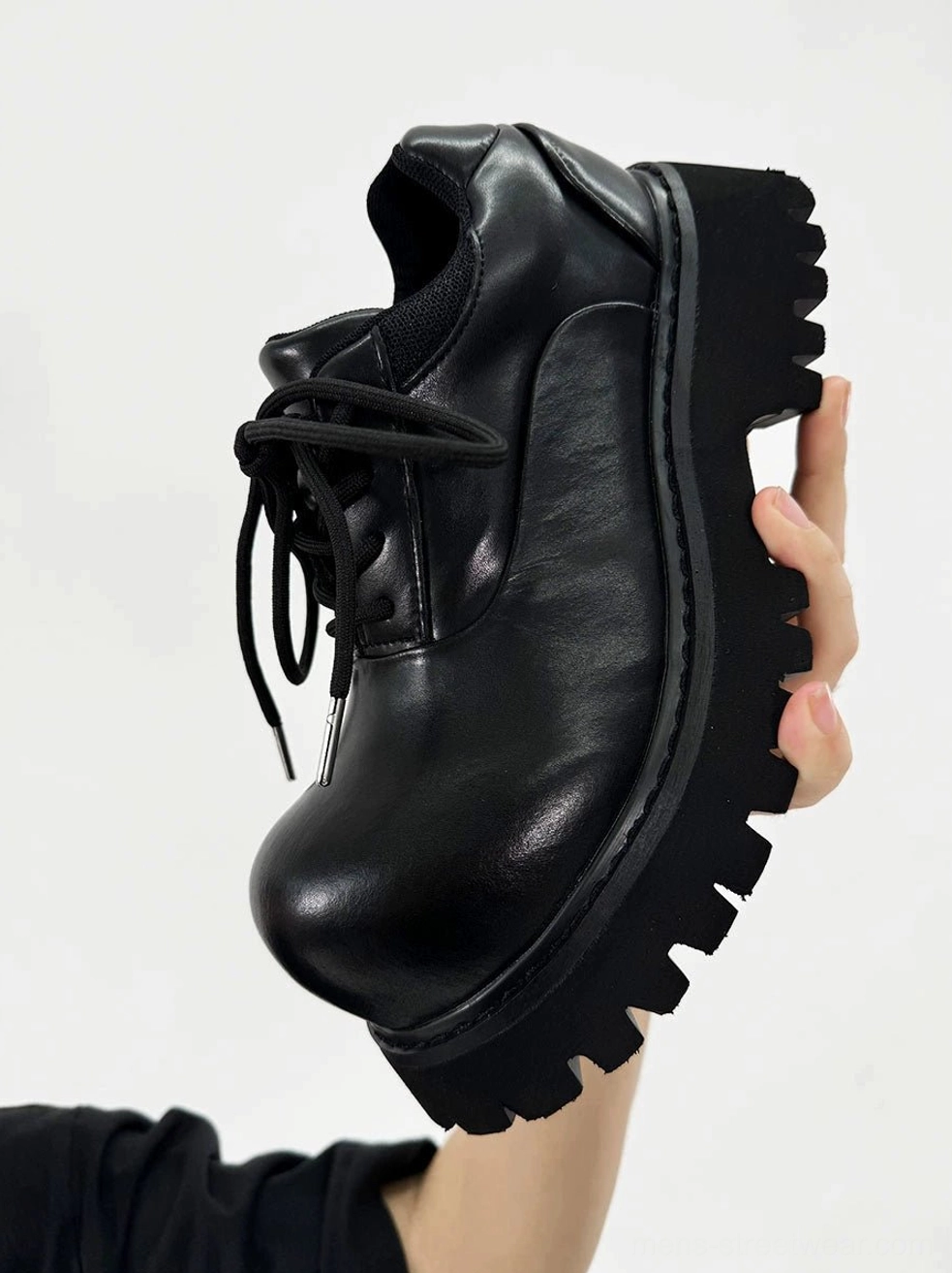 Close-up side view of polished black synthetic leather platform Derby shoe with chunky rubber lug sole