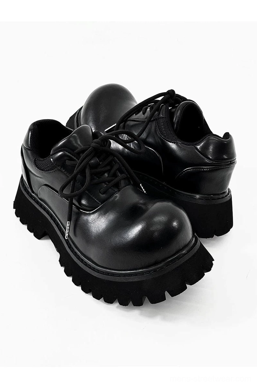 Pair of polished black platform Derby shoes with lace-up closure and thick rugged lug sole on white background