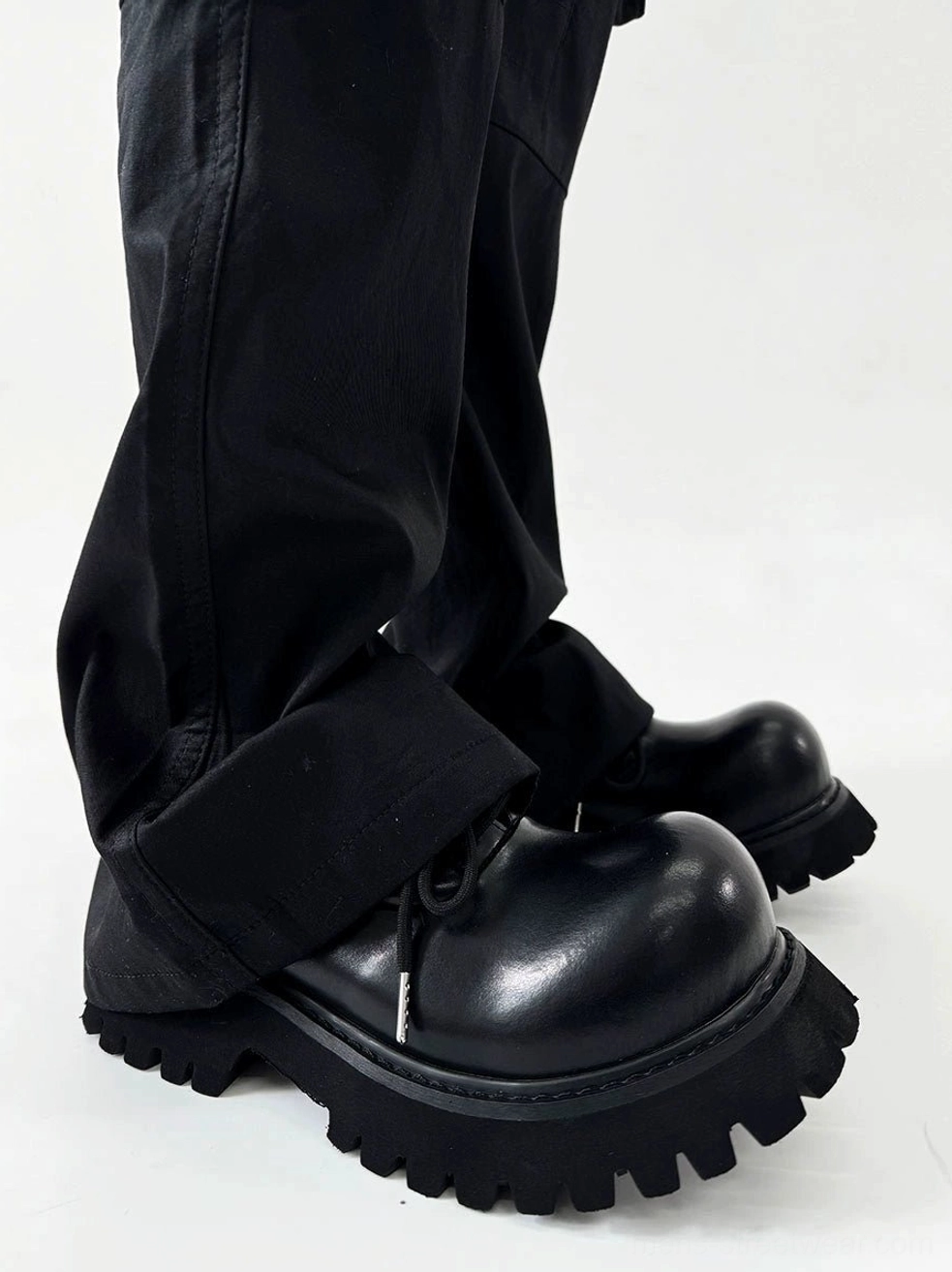 Side profile of polished black lug sole Derby shoes worn with loose black workwear trousers