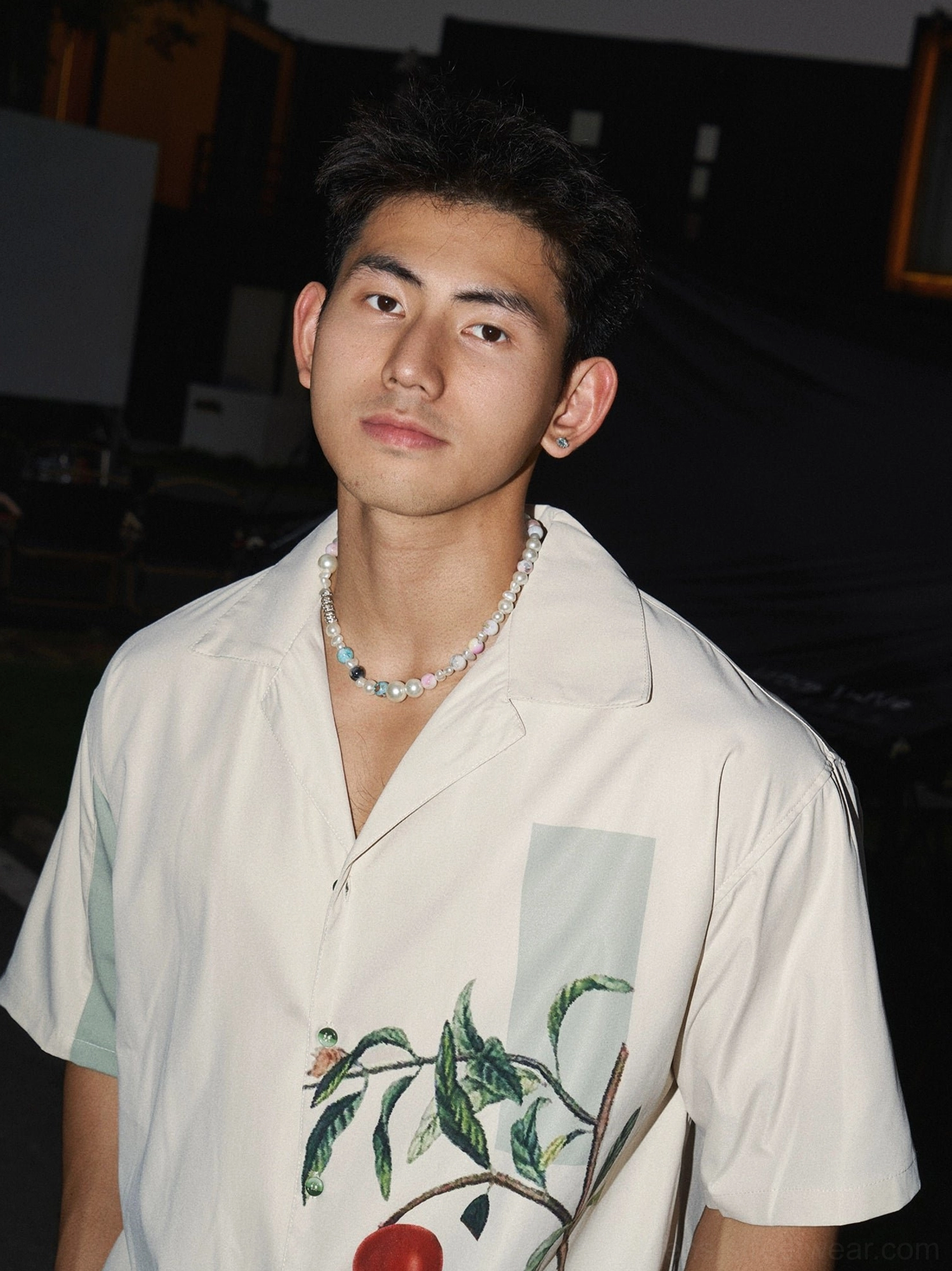 Close-up of a pomegranate botanical print camp collar shirt with light green sleeve accents styled with a pearl and turquoise beaded necklace