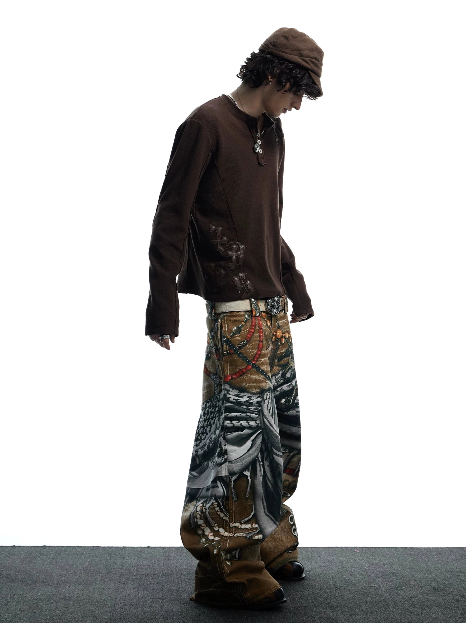 Side profile of printed wide-leg jeans displaying the clean side seam, oversized silhouette, and full tribal accessory-inspired pattern