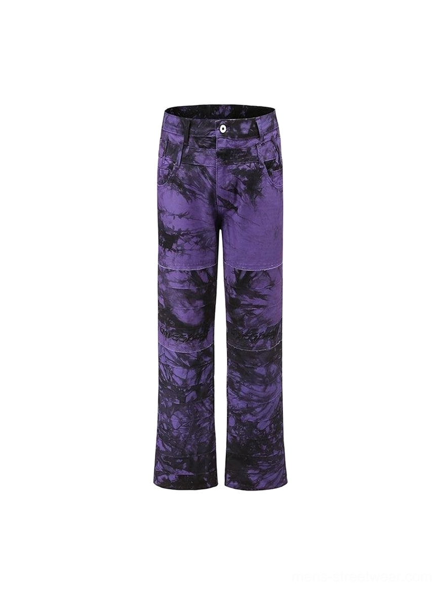 Purple and black tie-dye wide-leg flared streetwear trousers displayed from the front with a dramatic distressed finish
