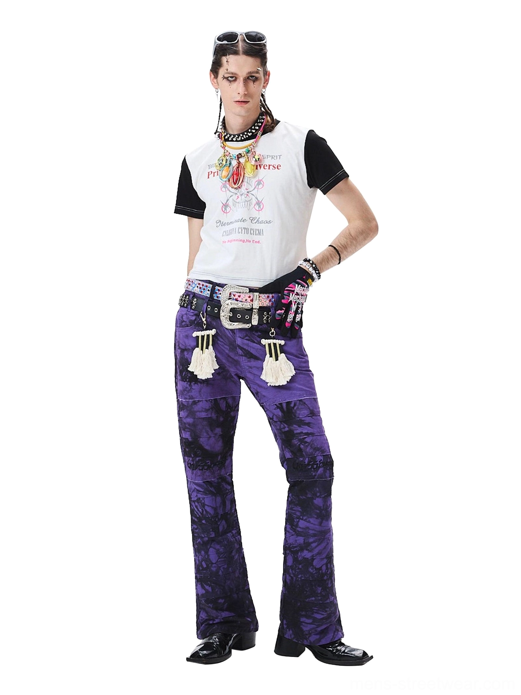 Three-quarter view of purple-black tie-dye wide-leg trousers styled with a decorative belt and hanging tassel accessories