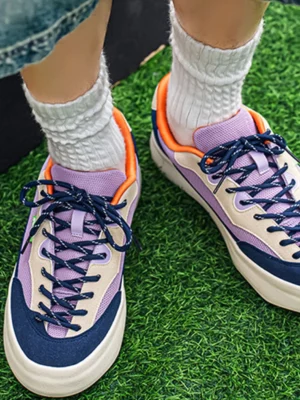 Purple colorblock platform streetwear sneakers worn with white ribbed socks and denim shorts in a top view