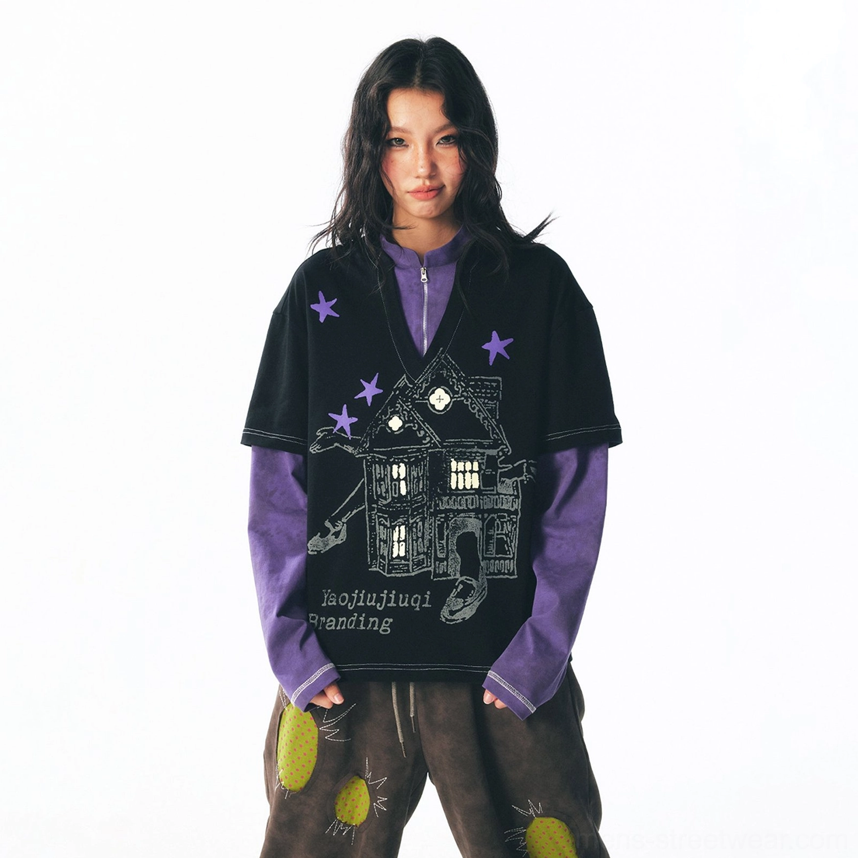 Female model wearing a purple half-zip mock-neck layered long sleeve tee with retro haunted house and star graphics