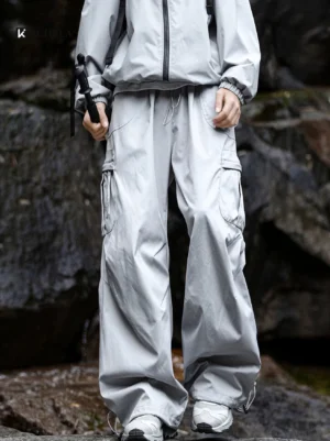 Model wearing light gray quick-dry wide-leg cargo pants with oversized utility pockets in a rocky mountain outdoor setting