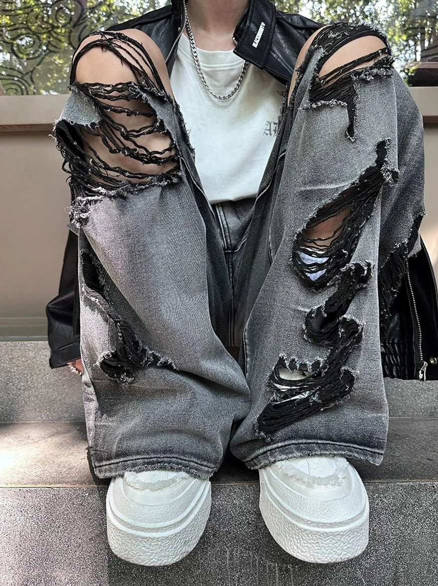 Top-down product view of oversized destroyed gray jeans with detailed frayed holes, faded denim wash, and wide-leg silhouette