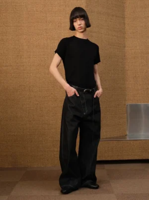 Three quarter front view of black wide leg balloon denim jeans with white contrast stitching and relaxed fit