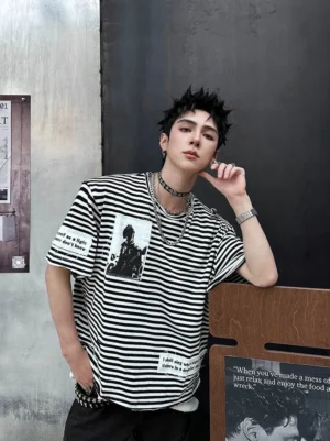 Front side view of an oversized black and white striped retro punk patch T-shirt with vintage portrait artwork, text tags, dropped shoulders, and layered hem