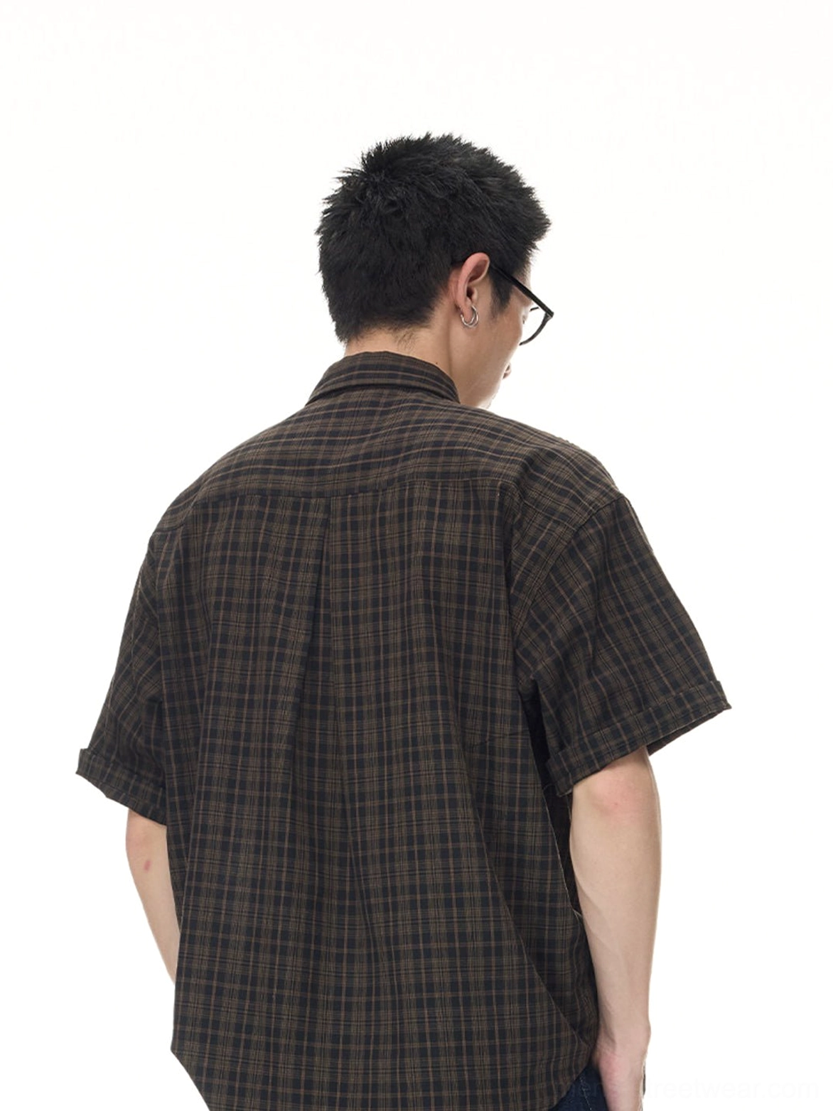 Rear view of a male model wearing a vintage brown plaid short sleeve shirt with full back pattern and dark frame glasses