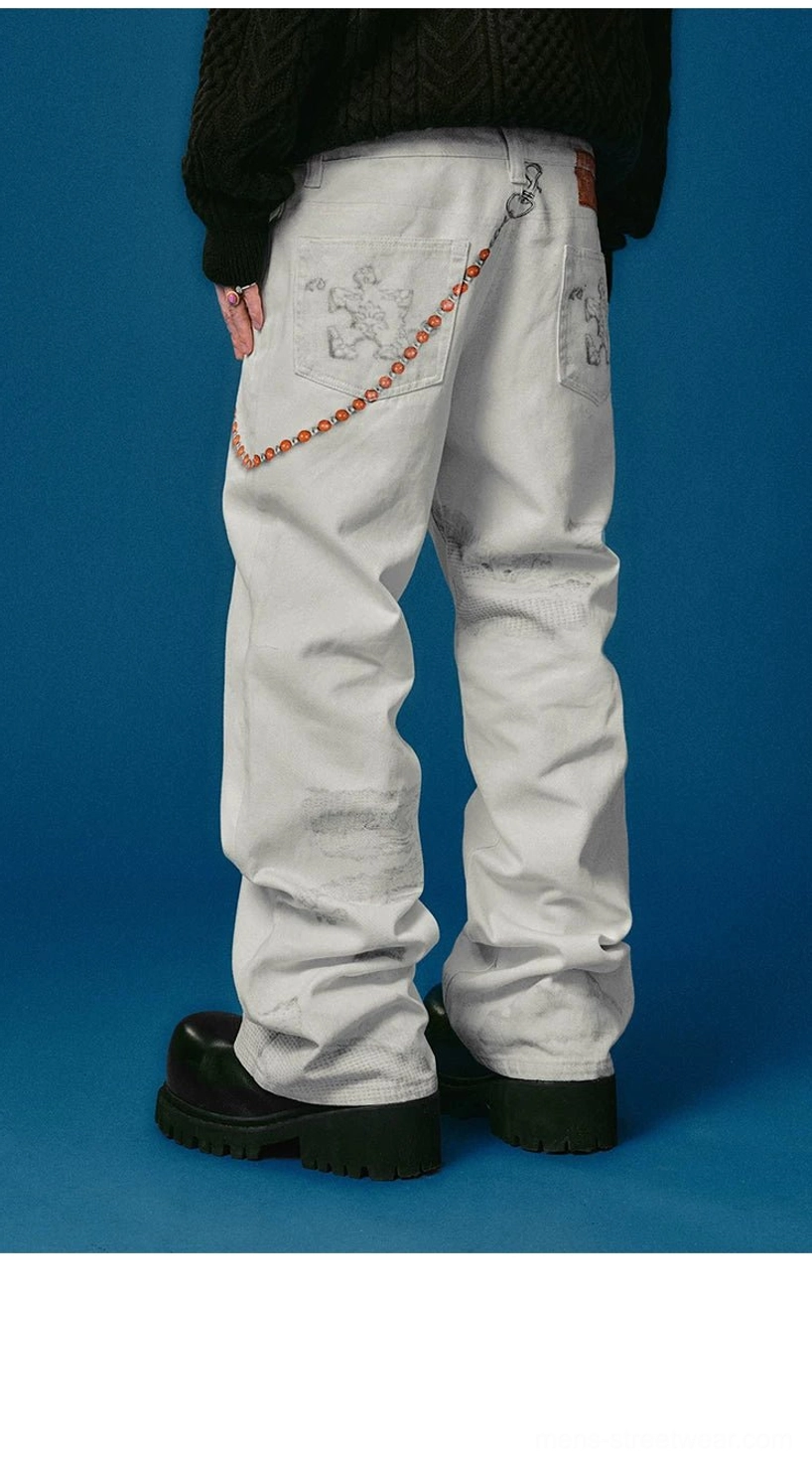 Reconstructed-style wide-leg jeans featuring textured distressed panels, five-pocket design, contrast stitching, and chain detail