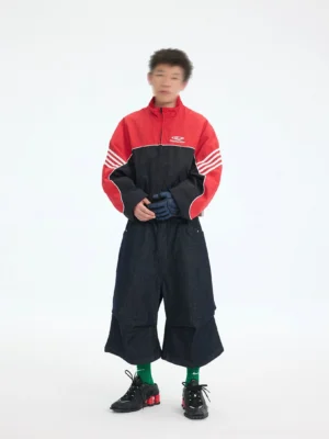 Men's red and black cropped track jacket with white racing sleeve stripes shown in a front full-body streetwear outfit