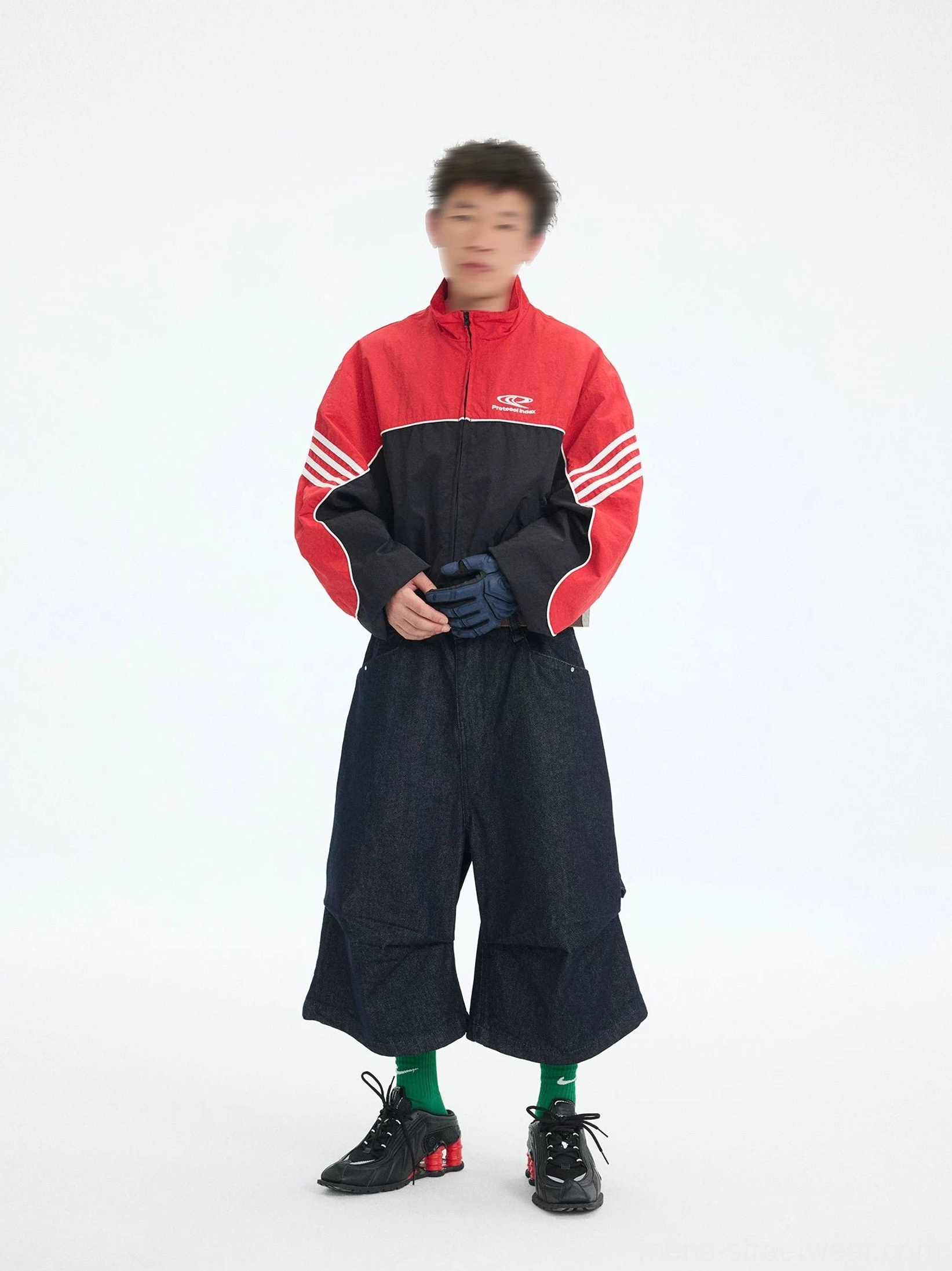 Men's red and black cropped track jacket with white racing sleeve stripes shown in a front full-body streetwear outfit