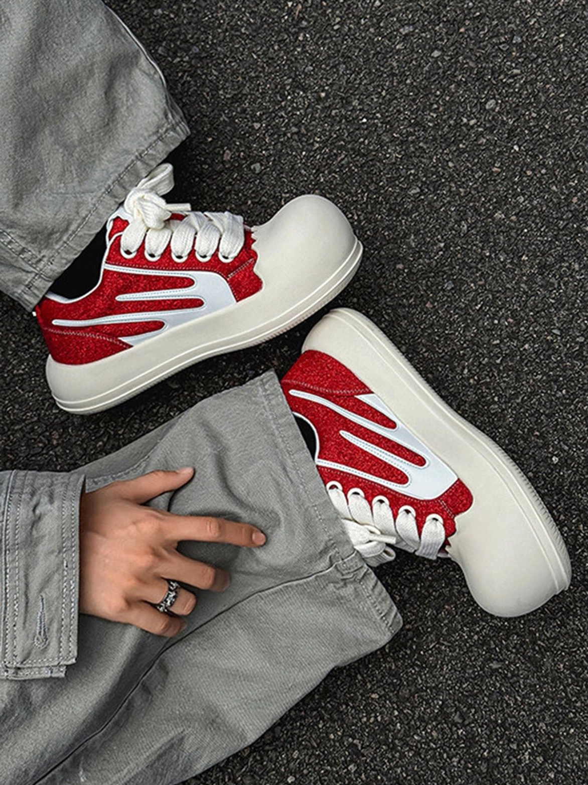 Red glitter chunky platform sneakers with white stripes worn with grey denim jeans in an outdoor streetwear flat lay