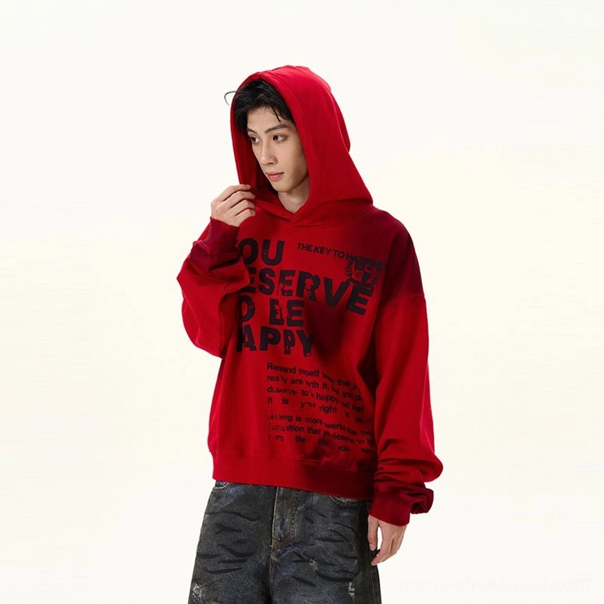 Right three-quarter front view of red graphic oversized hoodie with pulled-up hood, black slogan print, faded lower hem, ribbed cuffs, and relaxed fit