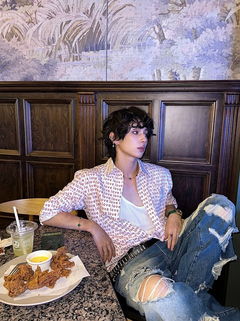 Side view of red love print long-sleeve button-up shirt styled open over a white undershirt