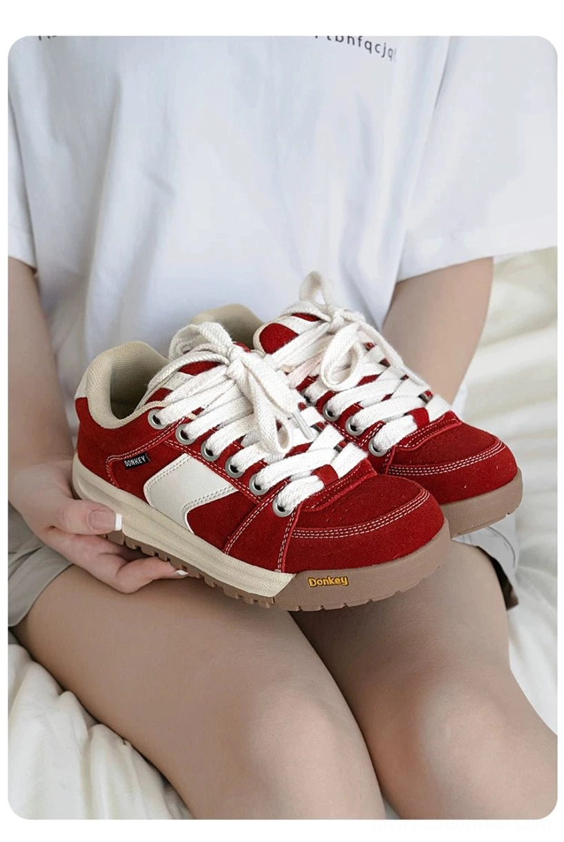 Red retro suede court sneakers placed on a casual outfit with white tee and shorts in an overhead lifestyle view