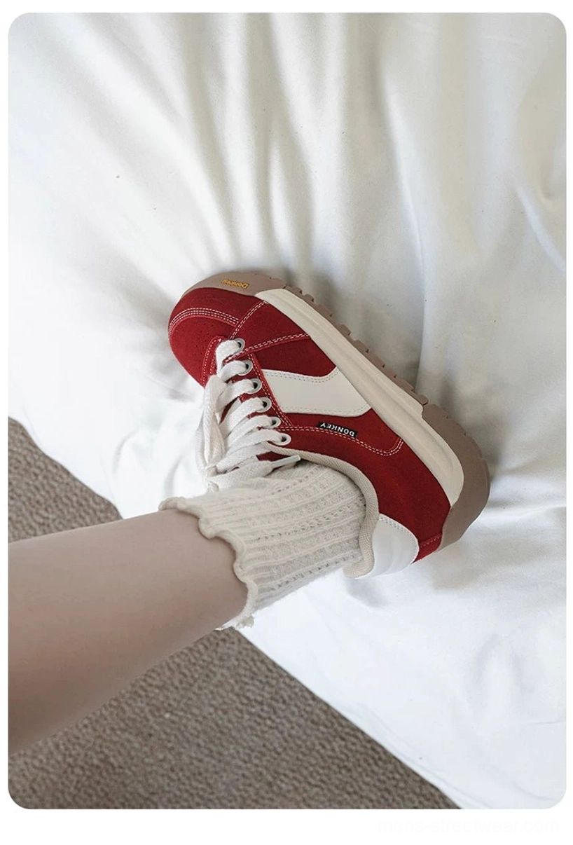Red suede streetwear court sneaker worn with ruffled white crew socks in a relaxed first-person footwear view