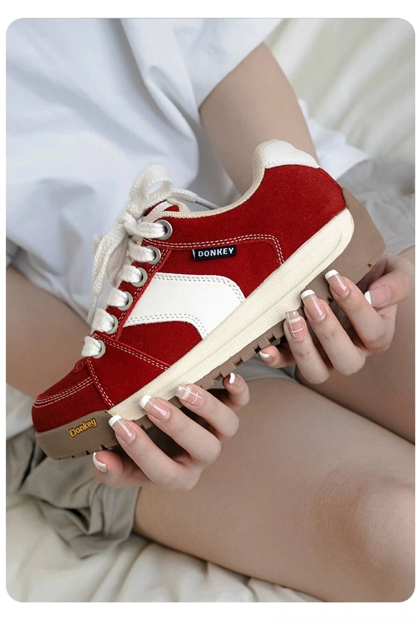 Close-up red suede court sneaker showing white side panel, white lace-up front, textured upper, and gum outsole