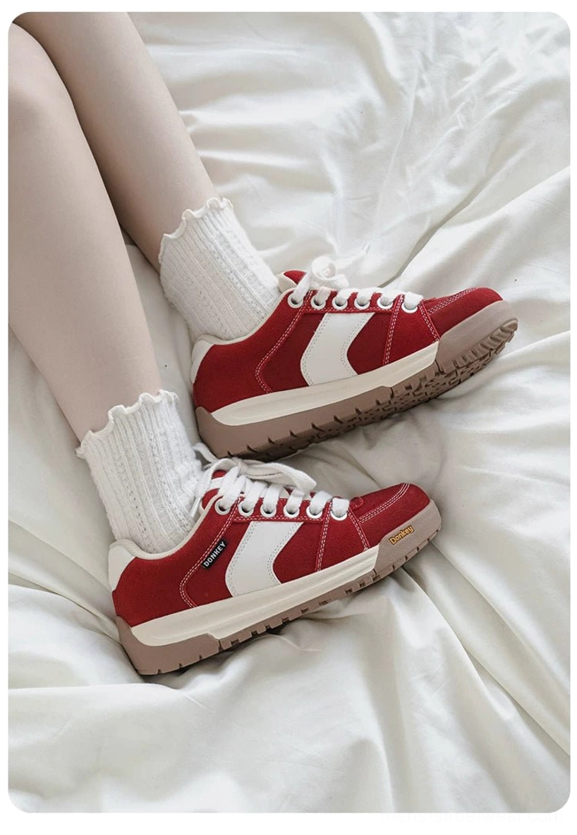 Pair of red suede court sneakers worn with white socks in an overhead casual streetwear styling photo