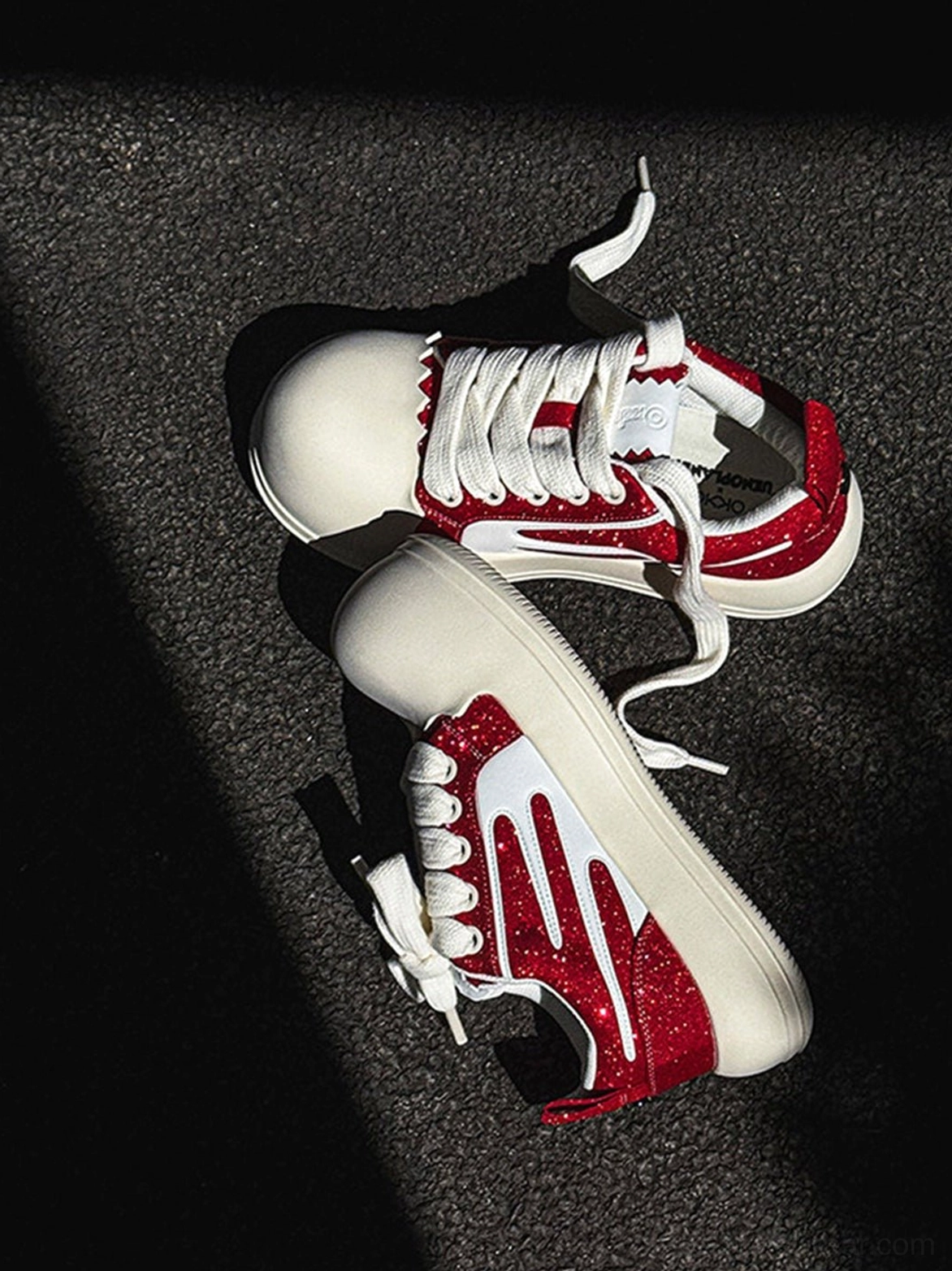 Top view of red and white glitter stripe chunky platform sneakers with white laces on dark asphalt ground