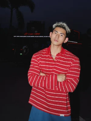 Three quarter view of a relaxed fit red and white horizontal striped rugby polo shirt with button placket styled for Korean street fashion