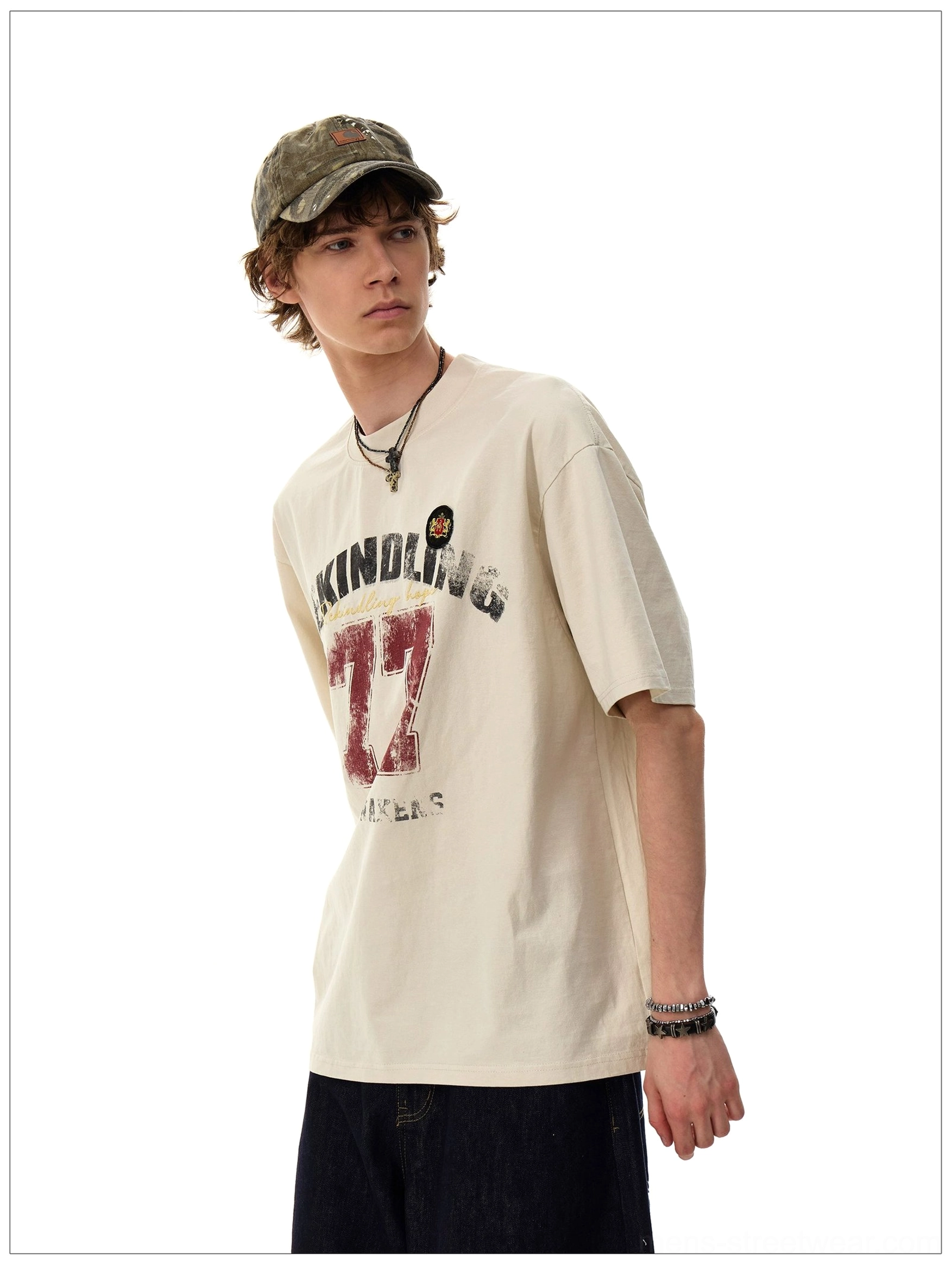 Side front detail of the Apricot Rekindling 77 oversized streetwear T-shirt with vintage varsity print and layered accessories