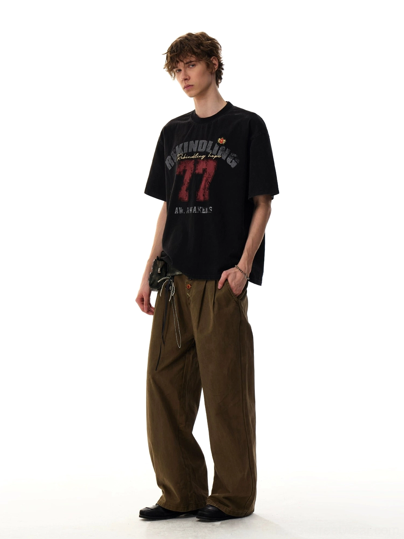 Full front view of the black Rekindling 77 distressed varsity number graphic streetwear T-shirt with cargo pants