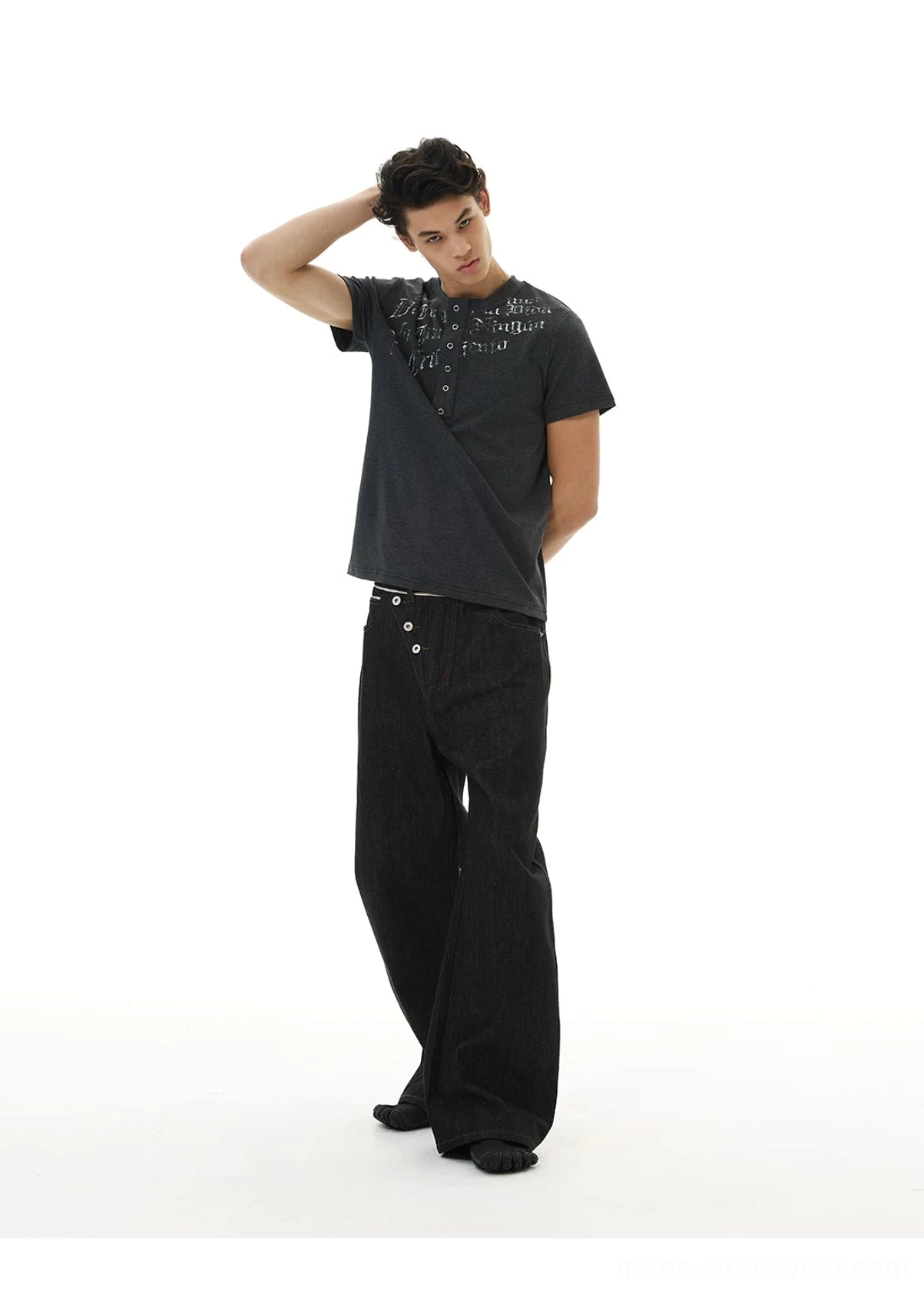 Side three-quarter view of relaxed baggy black denim jeans with asymmetric button waist and ultra-wide legs