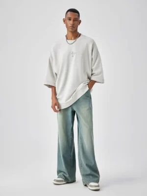 Front view of relaxed baggy wide-leg denim jeans in faded blue wash worn with an oversized crewneck T-shirt in a modern streetwear outfit