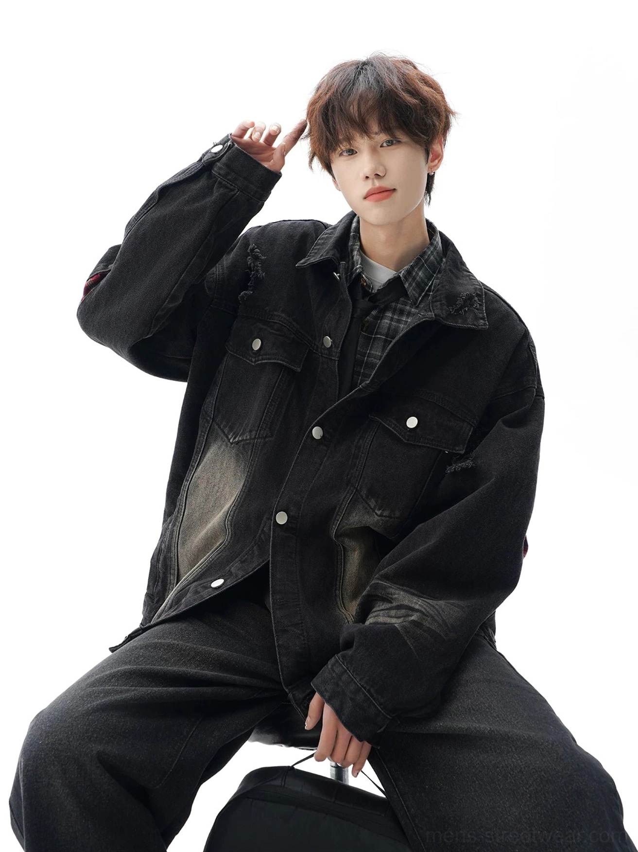 Relaxed black vintage denim jacket worn with a checkered shirt, featuring oversized proportions and faded workwear-inspired detailing