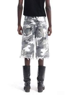 Rear view of relaxed camouflage denim cutoff shorts featuring a loose wide-leg silhouette, classic rear pockets, and frayed raw hem styled with a black cropped tank and mid-calf boots