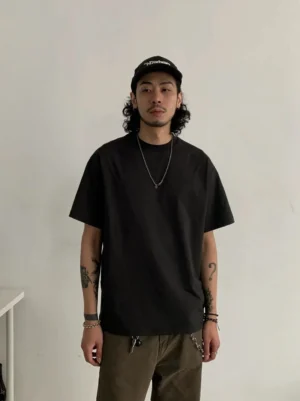 Relaxed solid color crew neck streetwear t-shirt styled on a male model with baseball cap and silver necklace in a minimalist studio