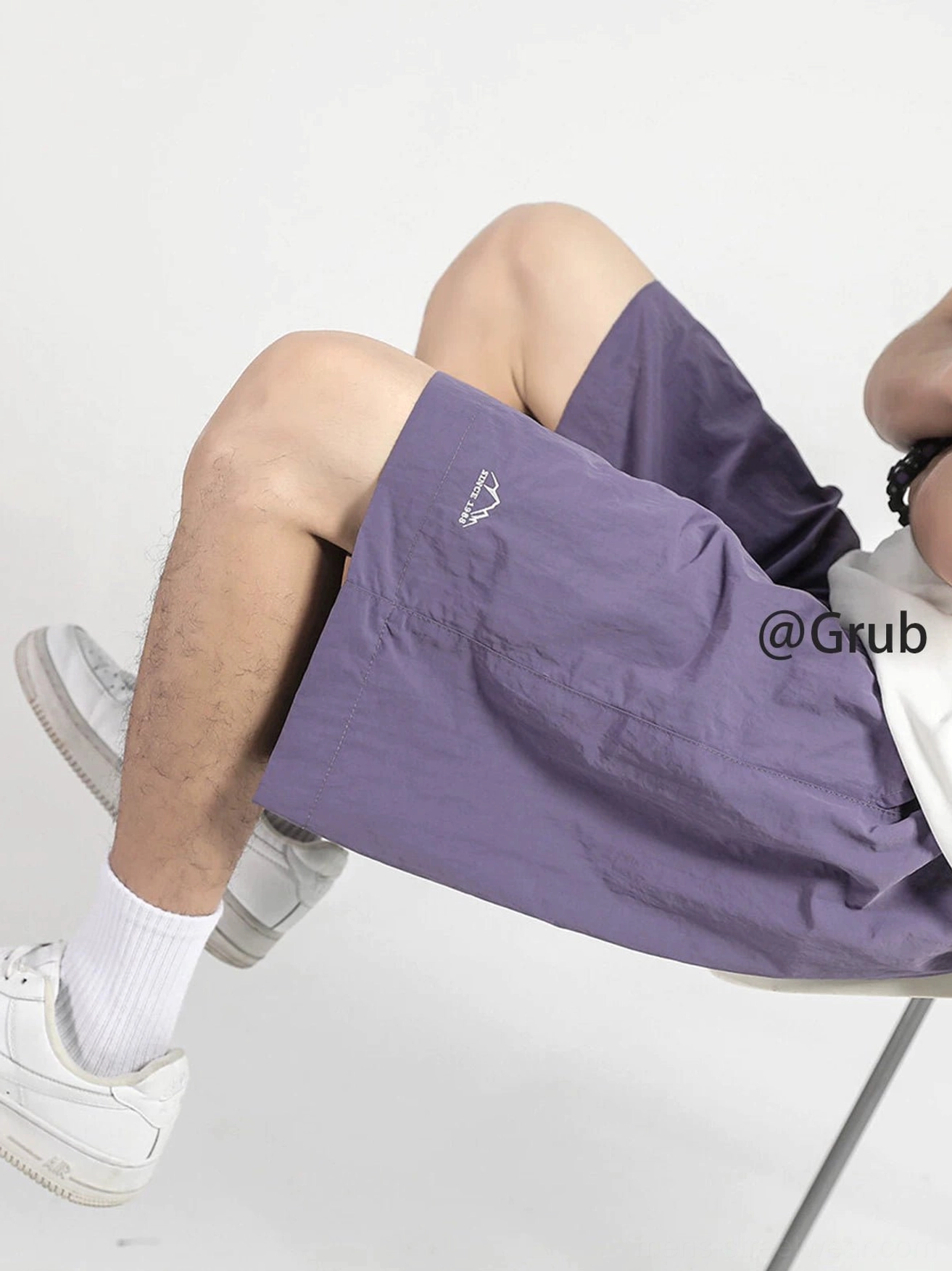 Dusty purple relaxed drawstring streetwear shorts shown in a low-angle side view with embroidered mountain hem logo