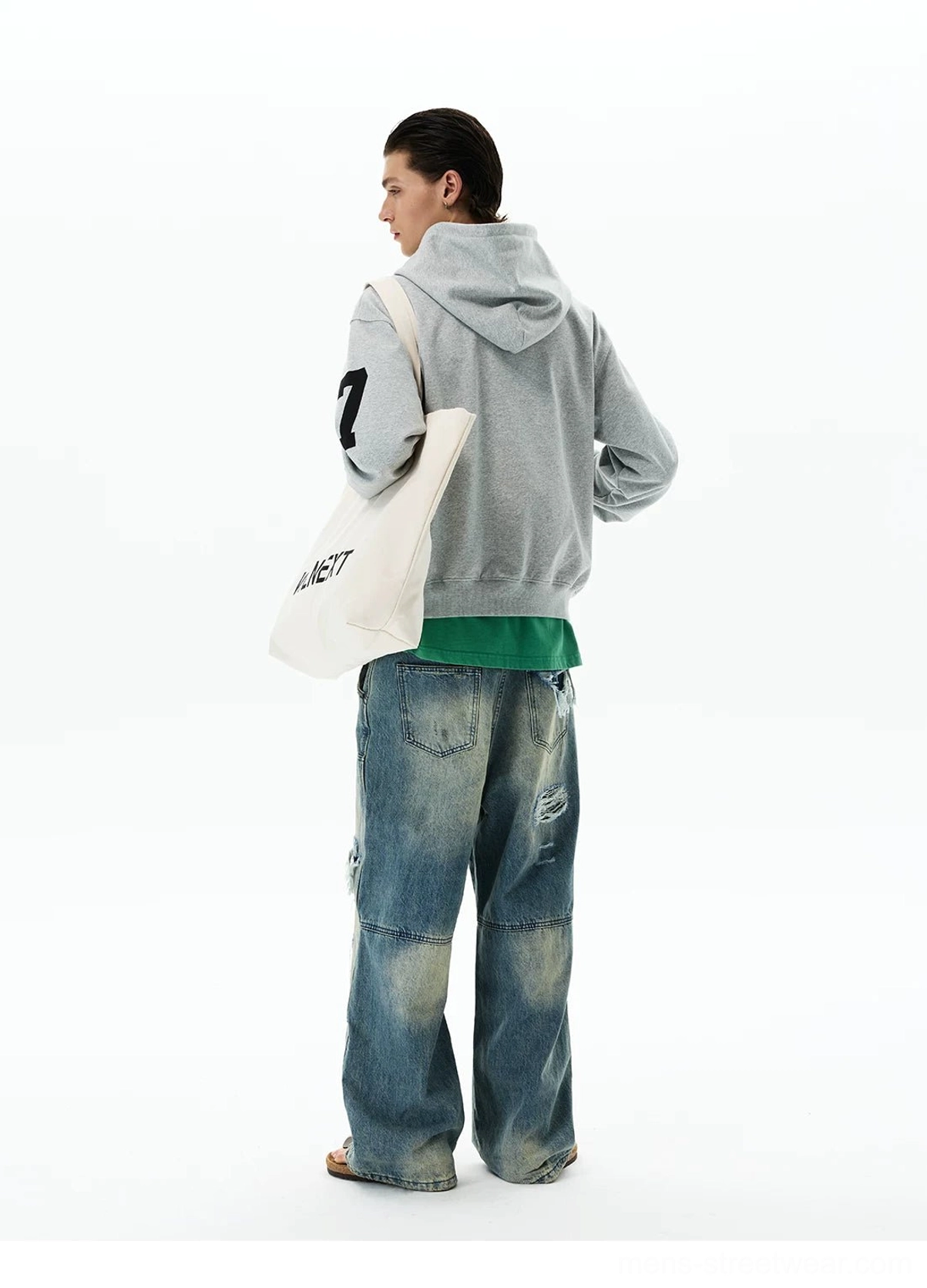 Rear three-quarter view of a relaxed heather grey crest zip hoodie showing the plain back, attached hood, sleeve number 7, and loose streetwear fit
