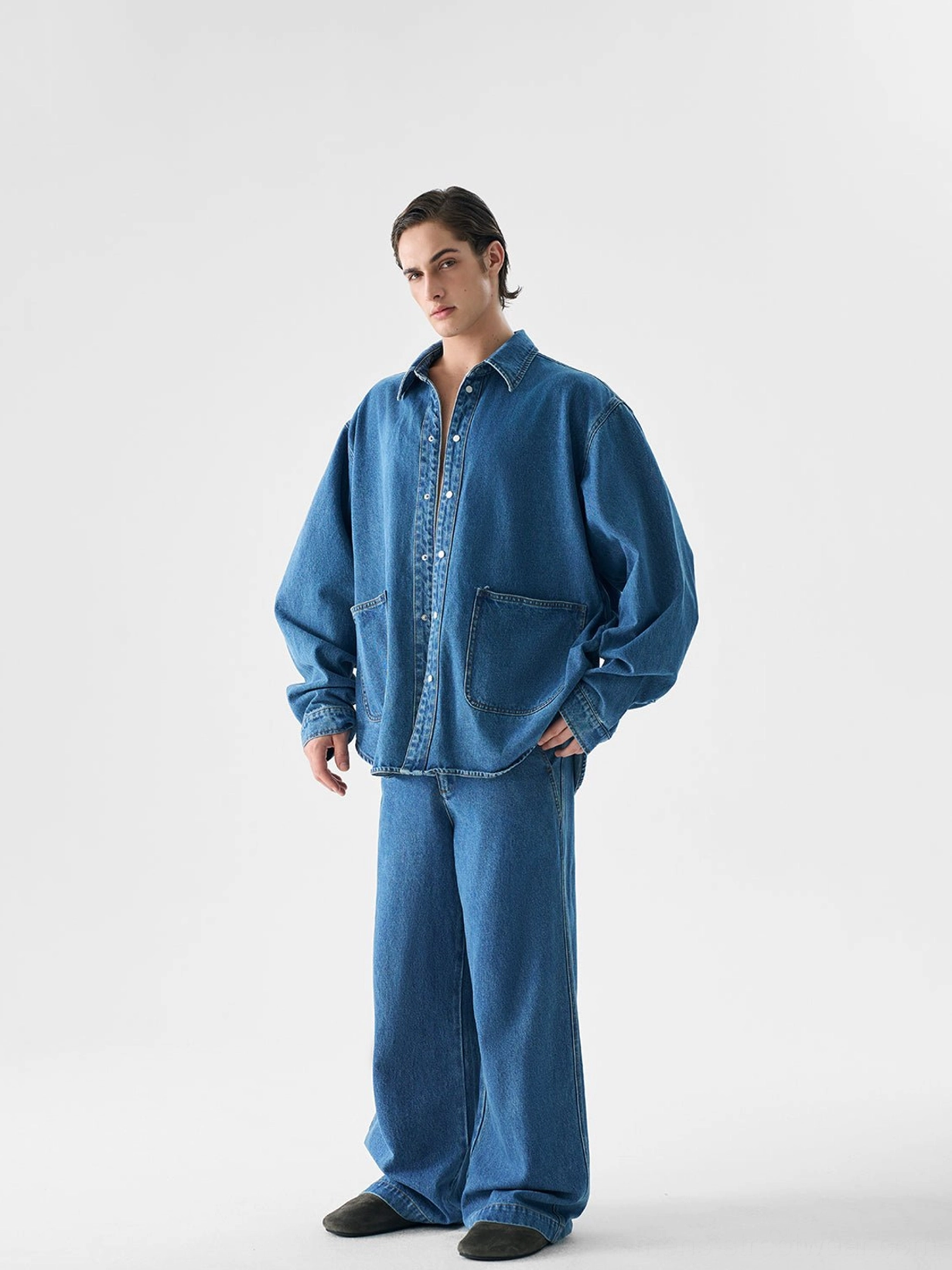 Three-quarter view of a relaxed oversized indigo denim shirt jacket with matching wide-leg trousers for Korean streetwear styling