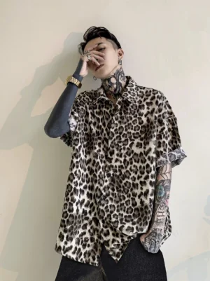 Front view of a relaxed leopard print satin shirt with rolled short sleeves button front closure and curved hem for Korean streetwear styling