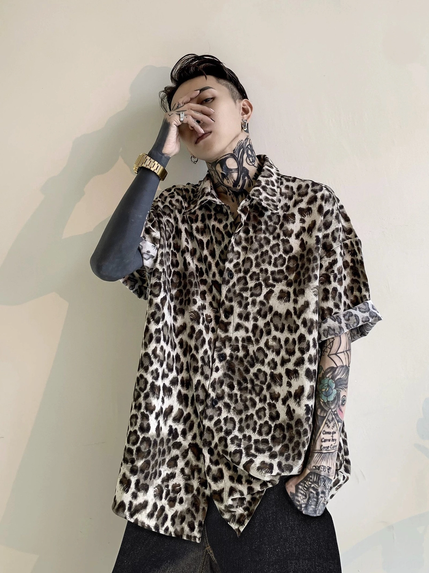 Front view of a relaxed leopard print satin shirt with rolled short sleeves button front closure and curved hem for Korean streetwear styling