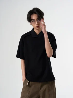 Black relaxed open collar knit polo tee front view with epaulet shoulder details on male model