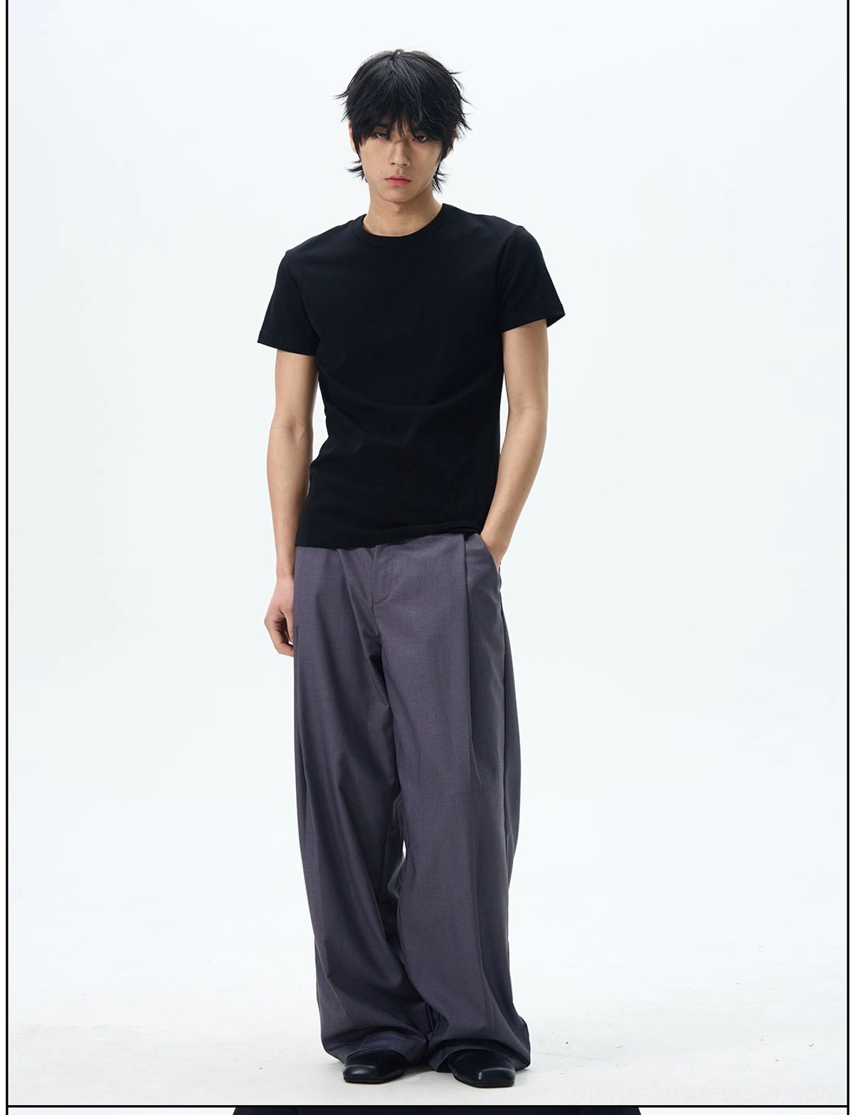 Male model styling relaxed dark slate grey pleated wide leg dress pants with a black t shirt