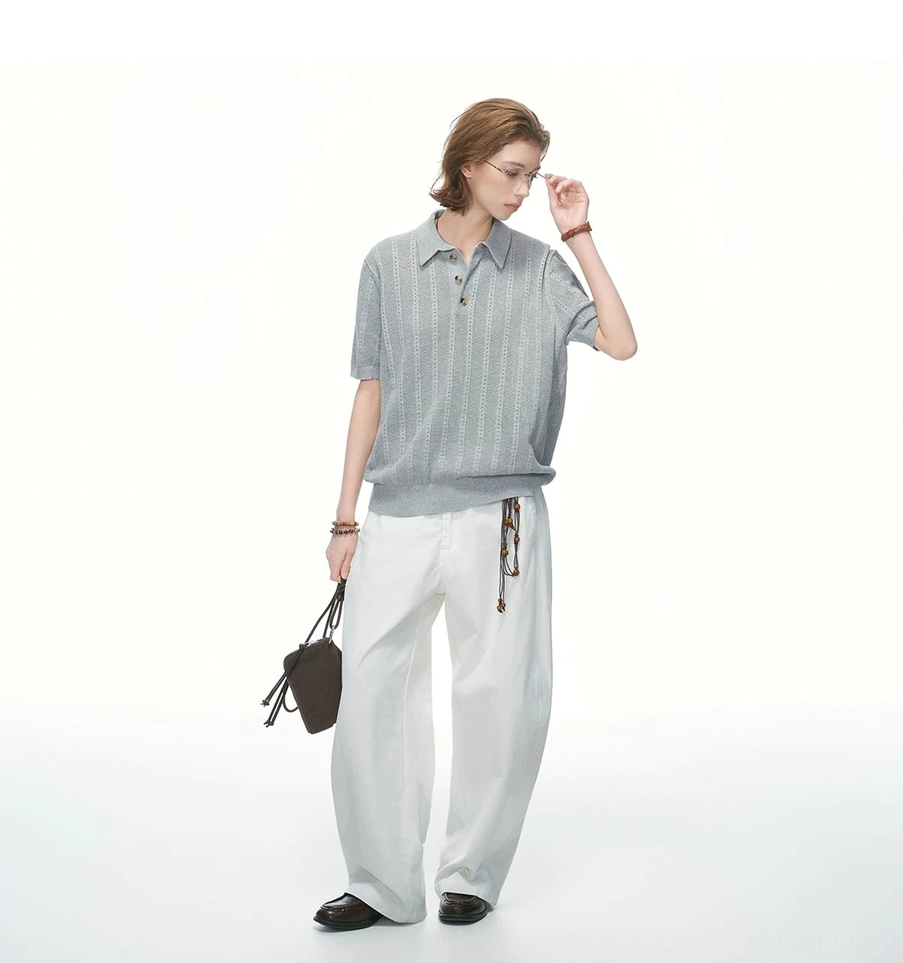 Relaxed heather grey pointelle knit polo shirt shown in a full-body side view with white wide-leg pants and waist chain