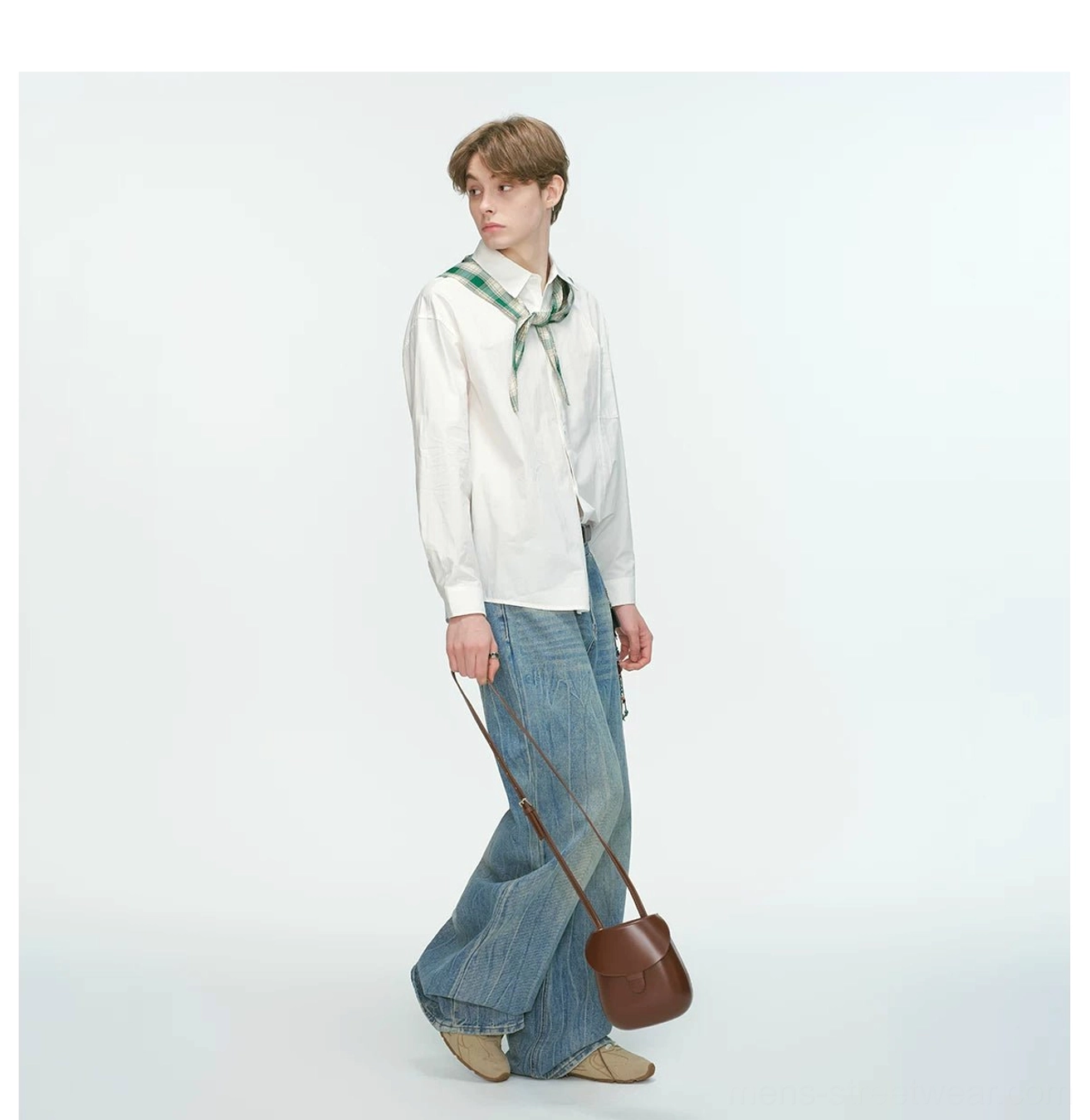 Side profile of a white relaxed poplin shirt with loose silhouette styled with wide-leg jeans and crossbody bag